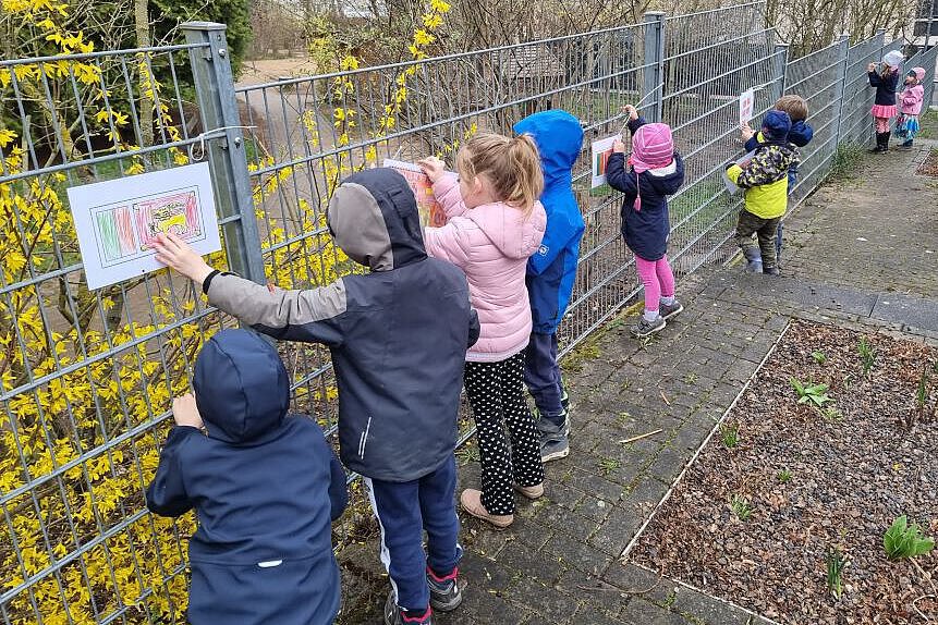 Kinder gestalten Vielfalt am Bauzaun Kinder befestigen selbst gestaltete Flaggen und Bilder am Bauzaun des Kindergartens, um internationale Vielfalt darzustellen.