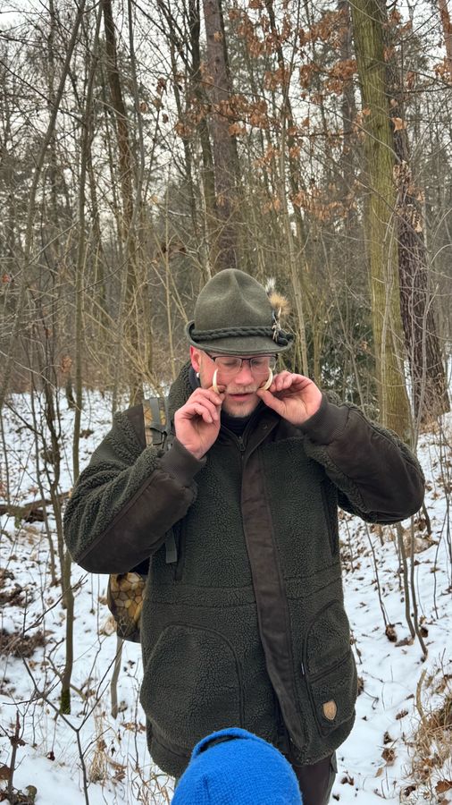 Jäger im Wald mit Wildschweinzähnen in der Hand Jäger im Wald mit Wildschweinzähnen in der Hand