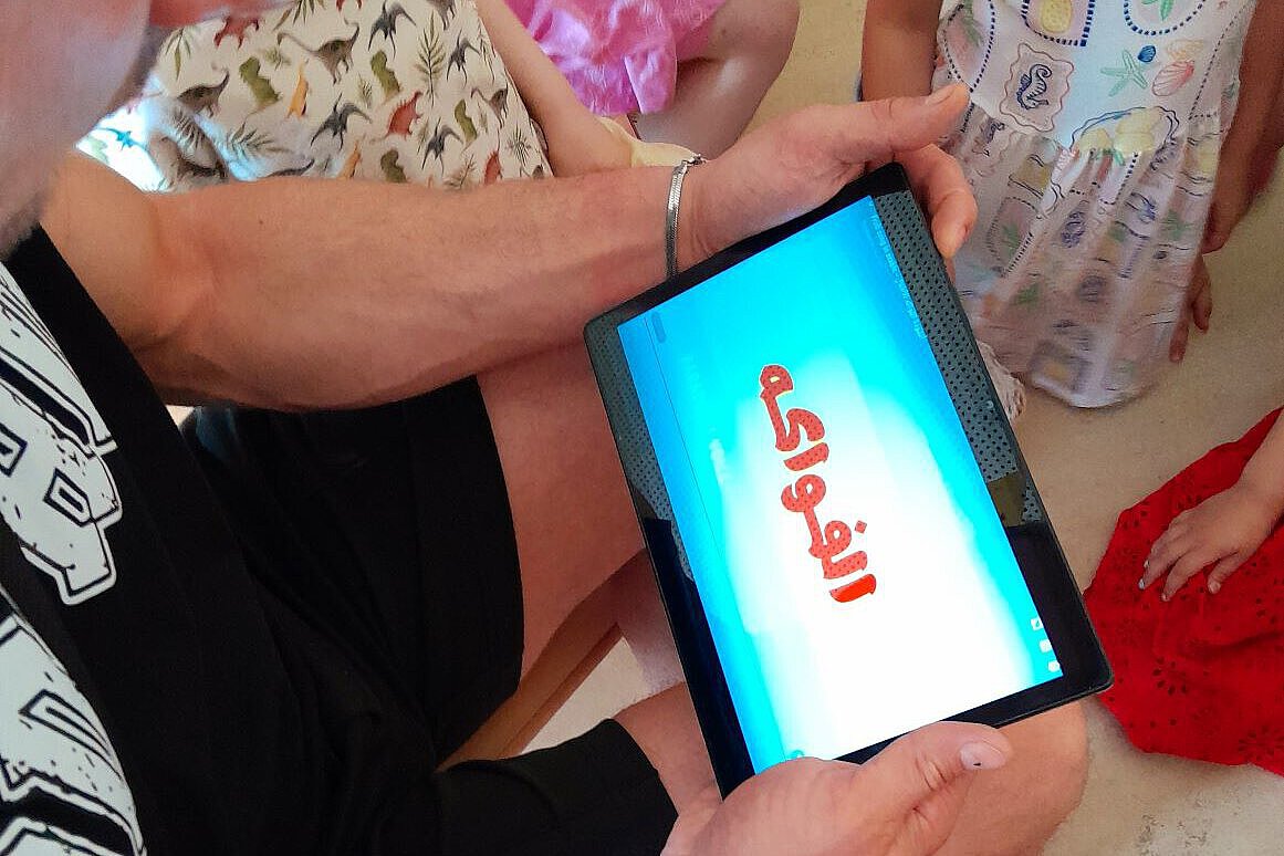 Digitales Lernen in der Kita – Medienpädagogik mit Tablets Pädagogische Fachkraft zeigt Kindern ein Tablet mit digitalem Inhalt im Kita-Alltag