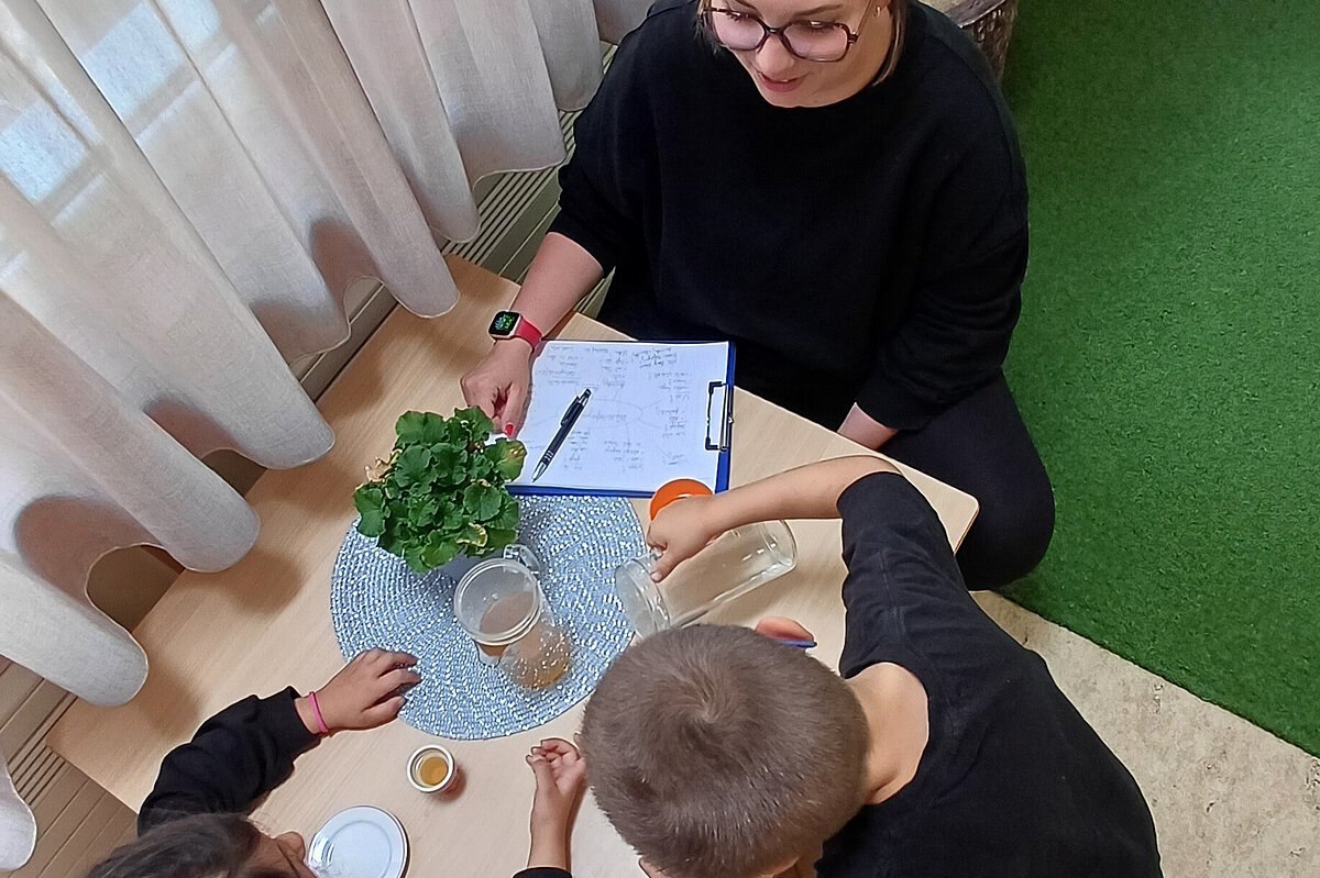 Pädagogische Fachkraft interviewt zwei Kinder, Teezeremonie