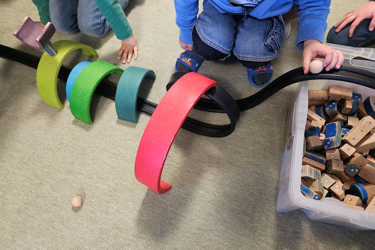 Kindergarten Vieselbach: Entdecken, Spielen und Lernen im Alltag Kinder spielen mit bunten Holzelementen und bauen eine Rennbahn für Kugeln.