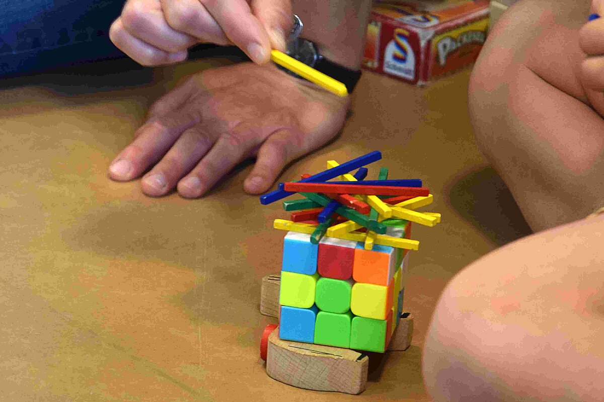 Erzieherin spielt mit Kind ein Spiel mit bunten Stäbchen und Würfeln