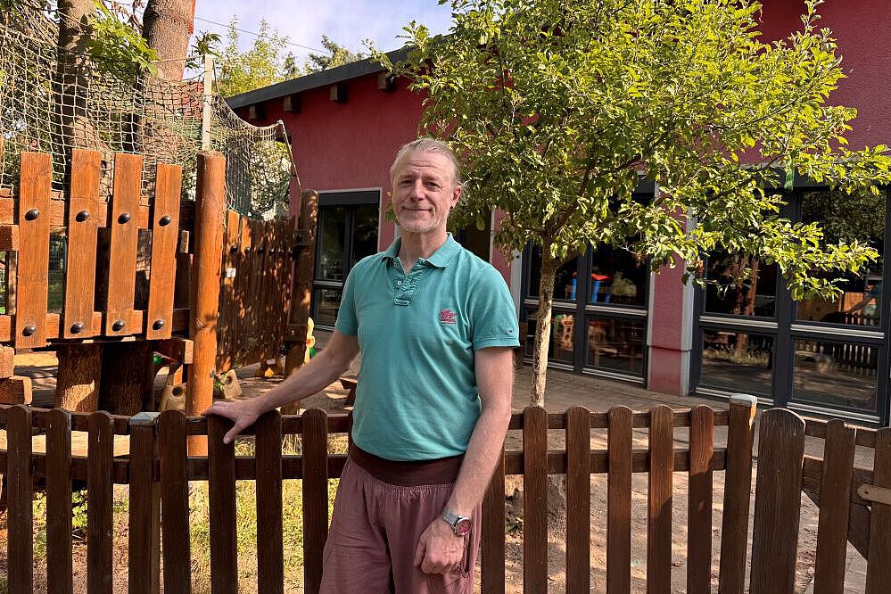 Im Interview mit Abschluss Praktikant André Polz-Tänzer aus dem Kindergarten Isserstedt Interviewpartner André Plz-Tänzer steht vor dem Spielplatz der Einrichtung Kindergarten Isserstedt und lächelt in die Kamera